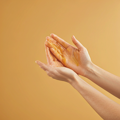 Warming Priaces Golden Body Oil in palms to activate botanical essences